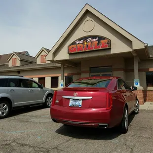 a red car parked in front of a restaurant