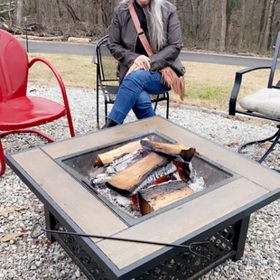 a woman sitting in front of a fire pit