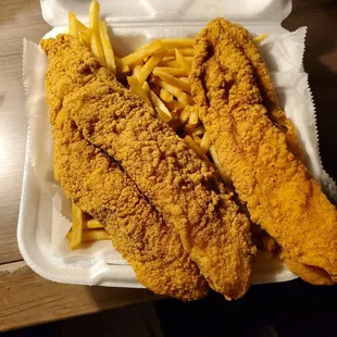 two fish and fries in a styrofoam container