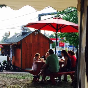 people sitting at picnic tables under umbrellas