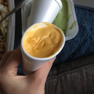 a hand holding a cup of mustard sauce