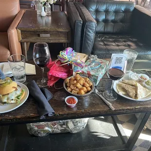 Coffee table in the casual sitting area laden with a Tate Farm burger, tots, the quesadilla plate, and beverages.