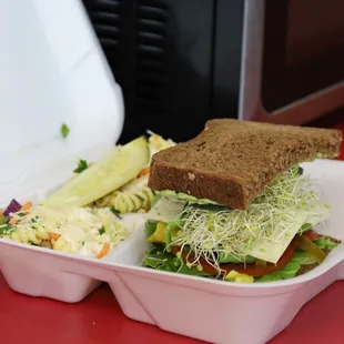 a sandwich and salad in a styrofoam container