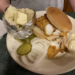 a plate of food including a sandwich, pickle, and potato salad