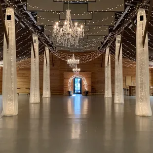 Fabric draping and chandeliers looking from the fireplace to the front door.