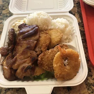 Seafood platter served with chicken, fish, shrimp, cabbage, broccoli, rice, and macaroni salad