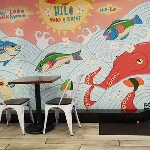 tables and chairs in front of a mural