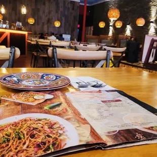 a menu and plates of food on a wooden table