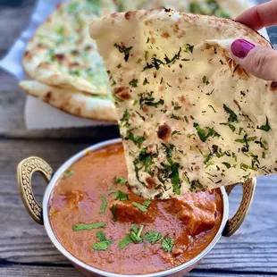 a hand dipping a piece of naan bread