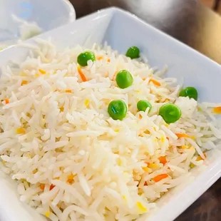 a plate of rice with peas and carrots
