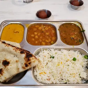 a plate of food with rice, naan, and curry