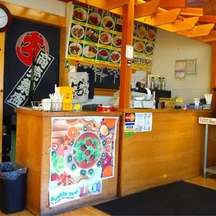 a restaurant counter with a menu on the wall