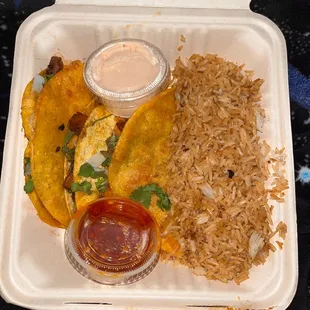 an open takeout container with rice and a side of sauce