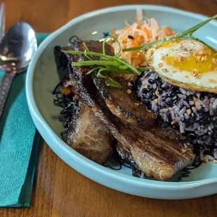 Tapsilog Filipino Rice Bowl. It has Roseda Beef Marinated in Soy Garlic with Heirloom Garlic Fried Rice and Atasara
