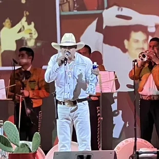 a man in a white cowboy suit singing into a microphone
