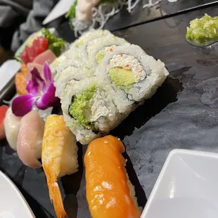 a variety of sushi on a black plate