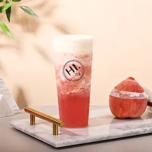a glass of watermelon drink and an apple on a marble tray