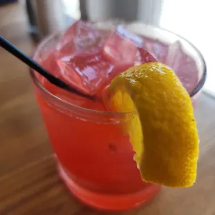 a pink drink with a lemon wedge