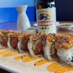 a plate of sushi with a bottle of beer in the background