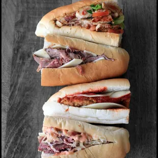 three sub sandwiches on a wooden table