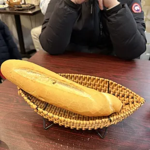 a person sitting at a table with a basket of bread