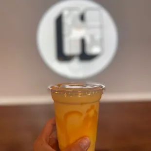 a hand holding a cup of orange juice