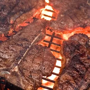 steaks cooking on a grill