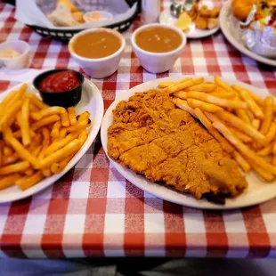 Country fried steak with brown gravy, French fries and French fries.