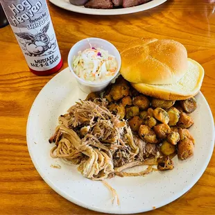 ows a pulled pork sandwich with coleslaw and potatoes
