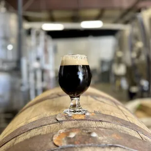 a glass of beer on top of a barrel