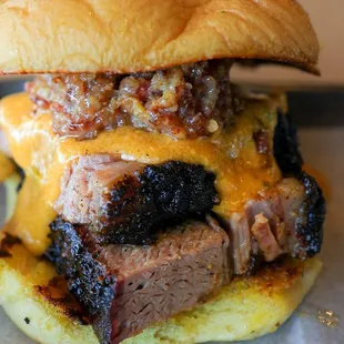 Brisket Queso. Brisket, Smoked Gouda Queso, and Bacon Jam on a Garlic Butter Grilled Potato Roll.