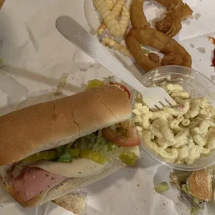a sandwich, macaroni salad and onion rings