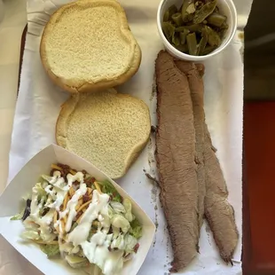 Sliced brisket sandwhich with a side salad and a side of green beans