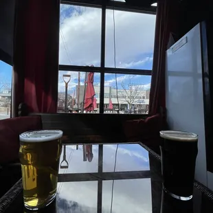a glass of beer on a table in front of a window
