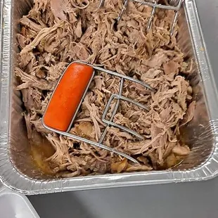 a roasting pan with pulled pork and carrots