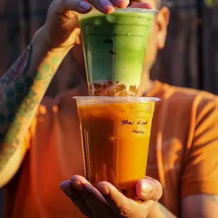 a man holding two cups of juice