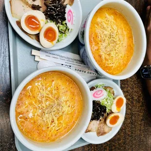 three bowls of ramen and a can of soda