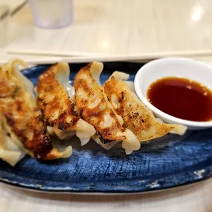 a plate of dumplings and a bowl of sauce