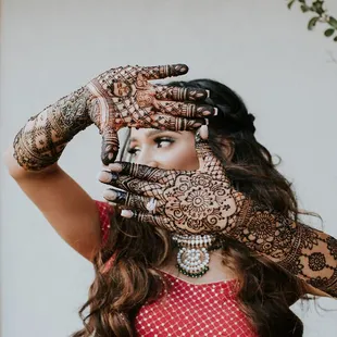 Indian bride frames her eyes with hands adorned by intricately filled mehndi designs.