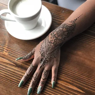 Paisley peacock with flowers and finger rings at a coffee shop henna appointment.