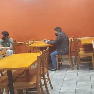two men sitting at tables in a restaurant
