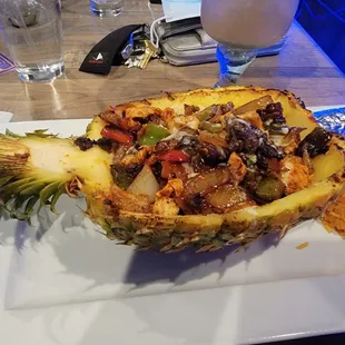 Piña Loca - grilled pineapple with chicken, steak, peppers, onions and a queso sauce