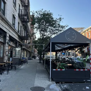 a sidewalk with tables and chairs