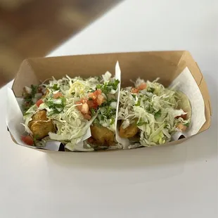Fish Ensenada Taco: BAJA Hand-battered, cabbage, onions, tomatoes, cilantro and crema |$2.89ea