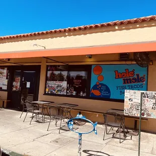the outside of a restaurant with tables and chairs