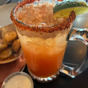 a glass of a drink with a lime garnish