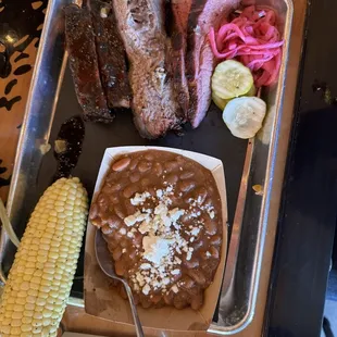 Combination of three meats, corn on the Cobb and beans