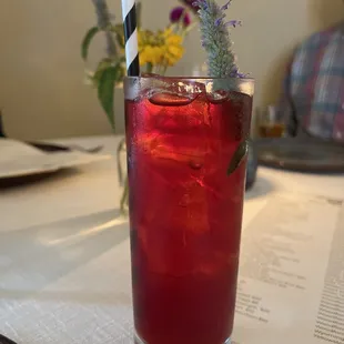 a glass of red drink with a striped straw