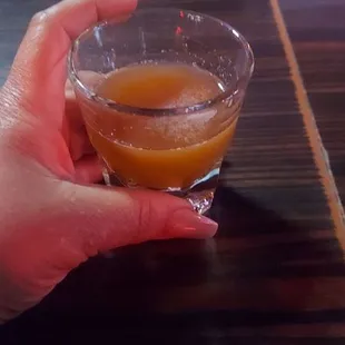 a hand holding a glass of orange juice