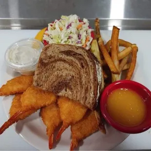 a plate of food including a sandwich, fries, coleslaw and coleslaw